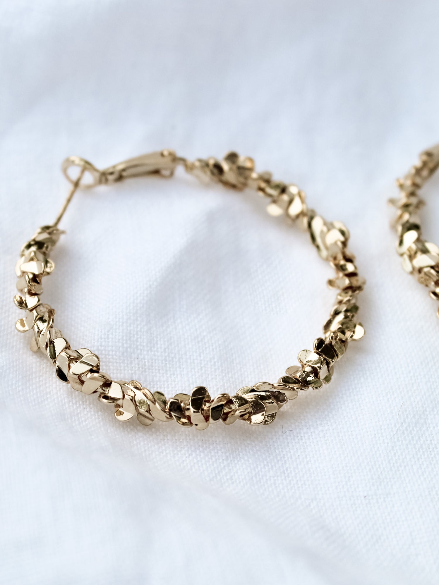 The Reese Hoop by Kinsey Designs Archives is a gold filled earring with leaf-shaped details, 1.5" in diameter, shown on a white fabric background.