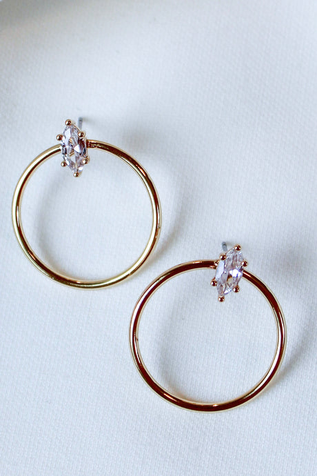 The Remi Hoop by Kinsey Designs Archives features marquise-cut cubic zirconia on 14K gold plated hoops (1" diameter), shown on a white textured fabric background.