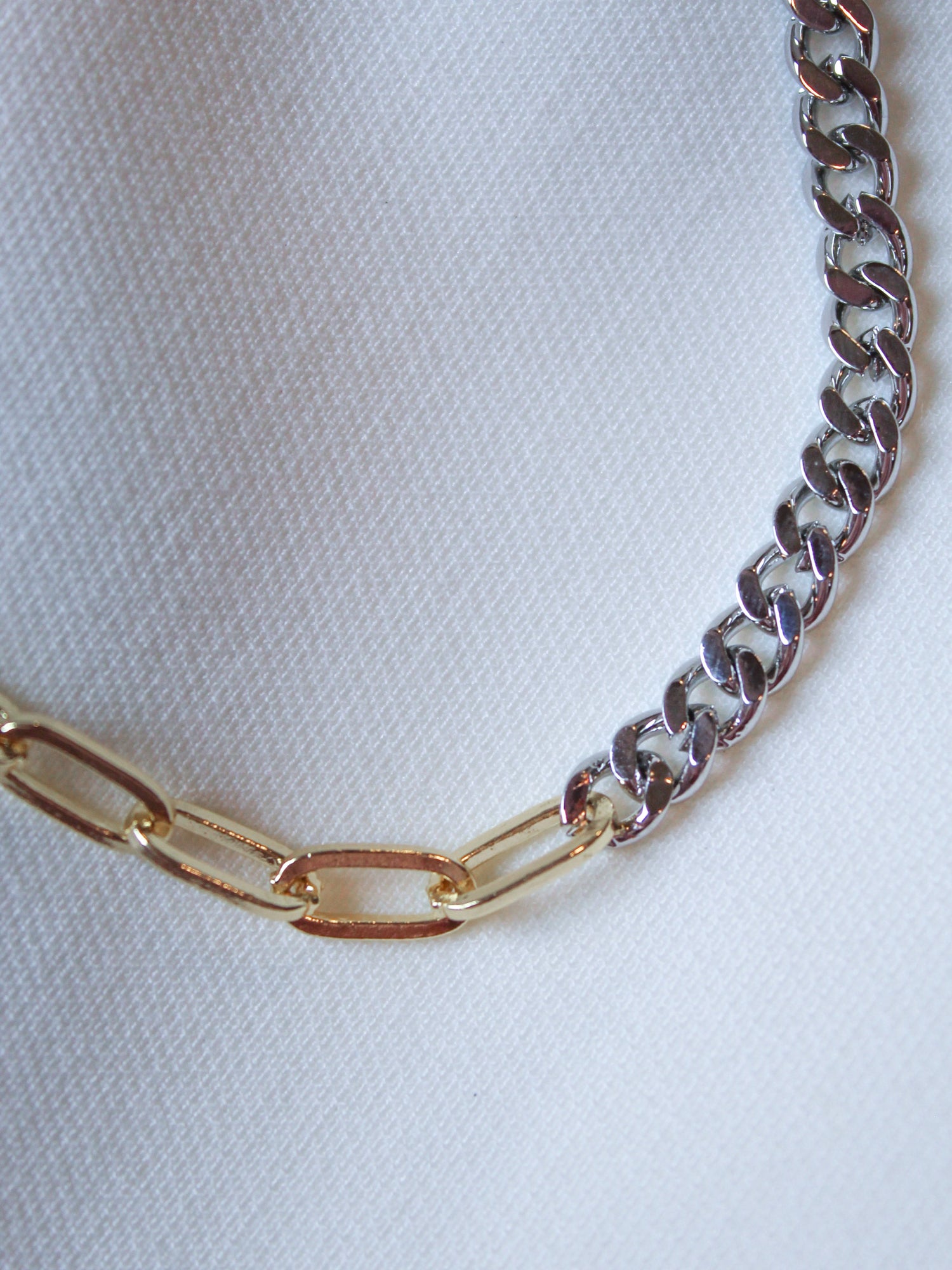 Close-up of the Saxon Mixed chain necklace by Kinsey Designs Archives, featuring gold and silver links on white textured fabric. Available in an 18" length as part of our exclusive sample sale.