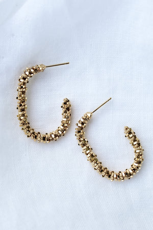 The Shea Hoop by Kinsey Designs Archives: gold plated textured hoops, .75" wide and 1.25" long, shown on a white fabric background.