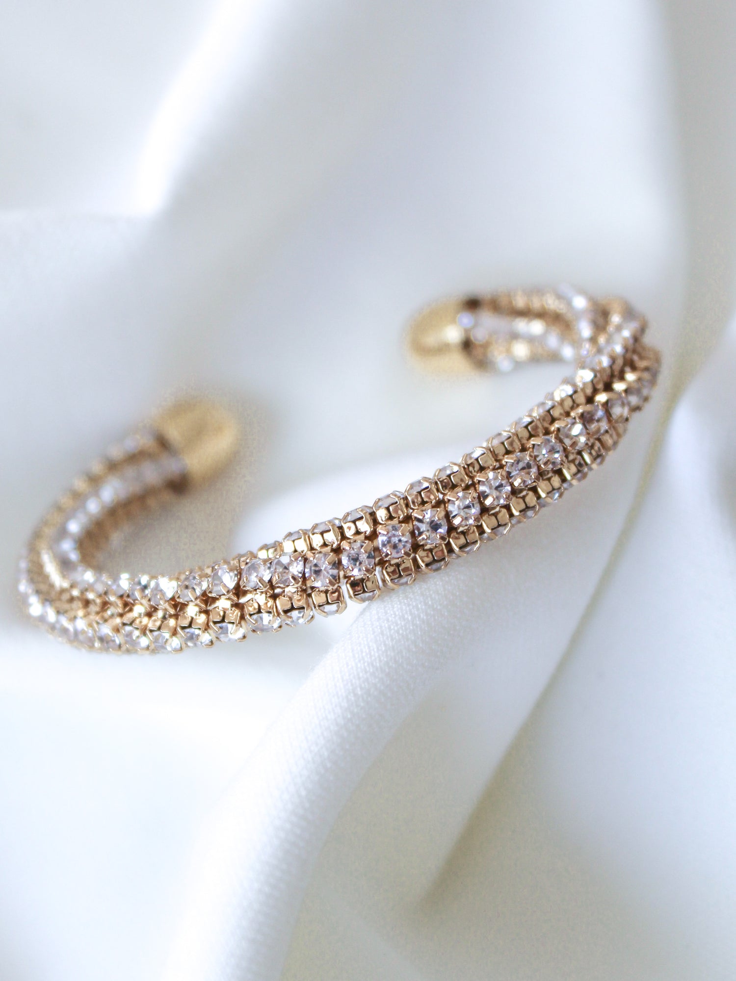 The Smog Cuff by Kinsey Designs Archives is a 16k gold plated brass adjustable bracelet with sparkling Cubic Zirconia, displayed on a white textured fabric background.
