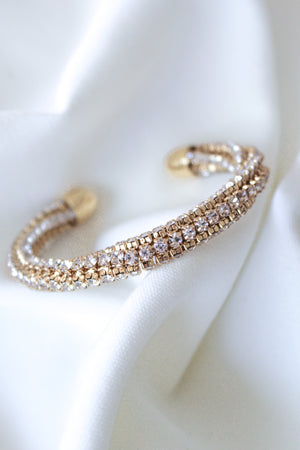 The Smog Cuff by Kinsey Designs Archives is a 16k gold plated brass adjustable bracelet with sparkling Cubic Zirconia, displayed on a white textured fabric background.