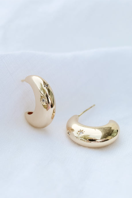 The Swen Earring by Kinsey Designs Archives features .75" wide gold hoops with small star-shaped cubic zirconia, shown on a white fabric background.