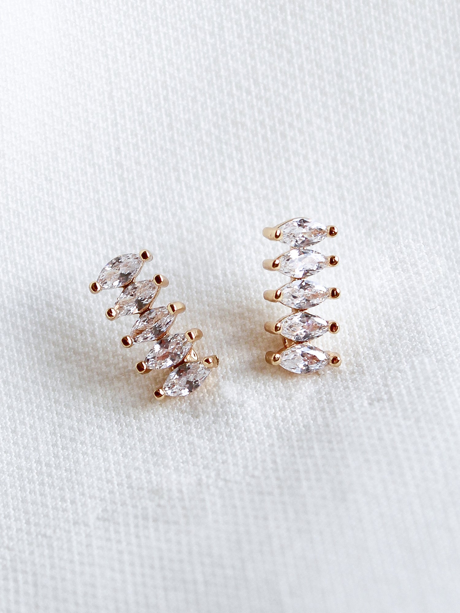 The Winnie Post earrings by Kinsey Designs Archives feature five marquise-cut cubic zirconia stones each and are displayed on a white textured fabric background.