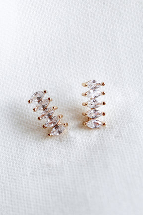 The Winnie Post earrings by Kinsey Designs Archives feature five marquise-cut cubic zirconia stones each and are displayed on a white textured fabric background.