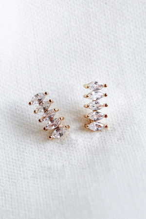 The Winnie Post earrings by Kinsey Designs Archives feature five marquise-cut cubic zirconia stones each and are displayed on a white textured fabric background.