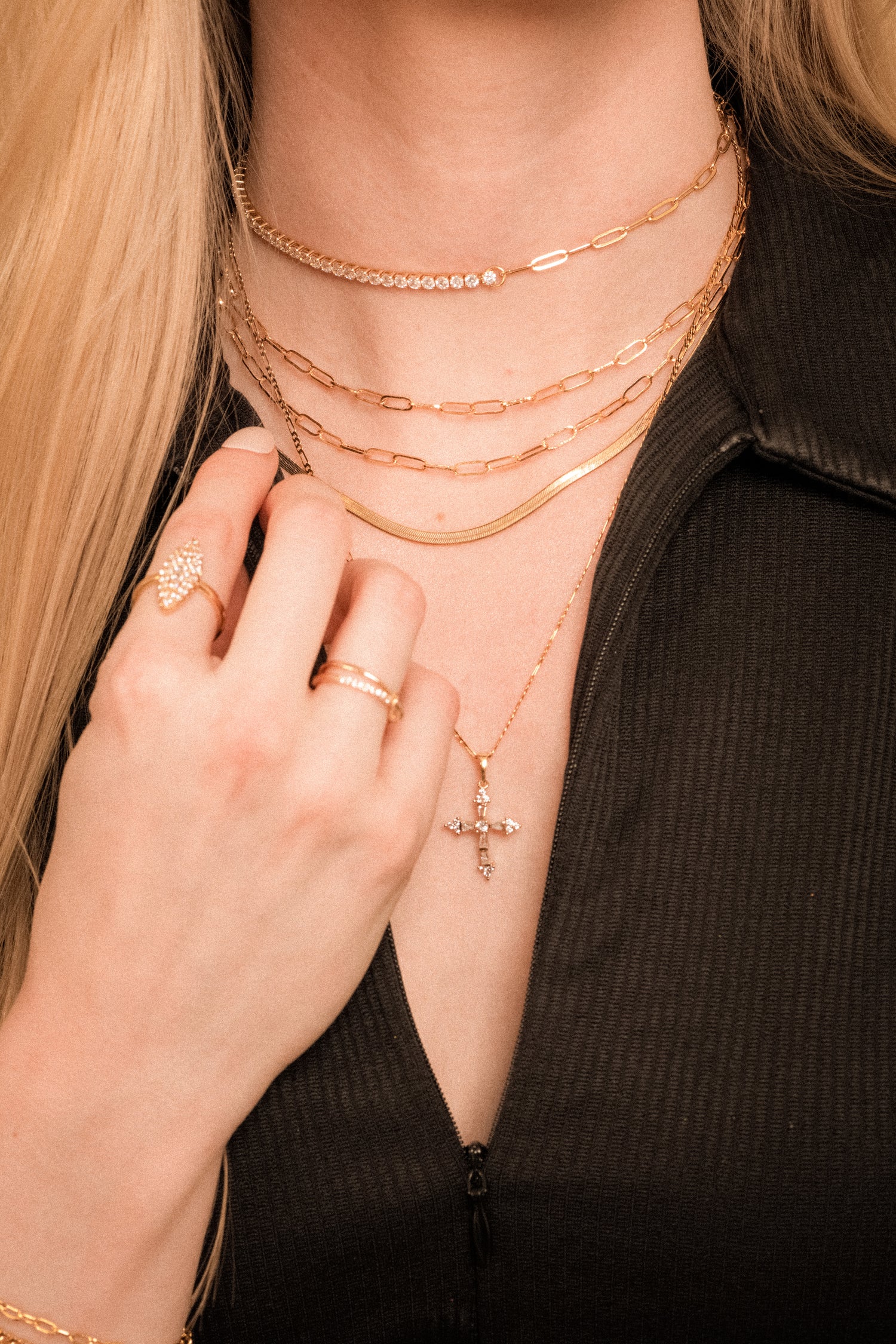 Woman in a black top wearing the Kinsey Designs Archives Wren Chain Layer 16k gold plated necklace, styled with rings and a cross pendant.