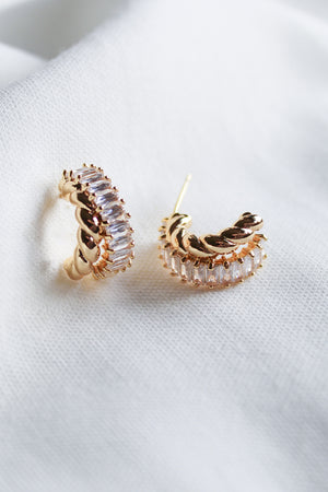 The Zuri Hoop by Kinsey Designs features gold filled earrings accented with clear cubic zirconia, elegantly presented on a soft white fabric background.