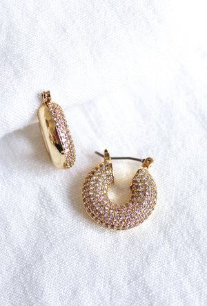 The Mikki Pave Hoop by Kinsey Designs Archives features gold plating and small sparkling stones, measures .75" wide, and is displayed on a white textured fabric background.