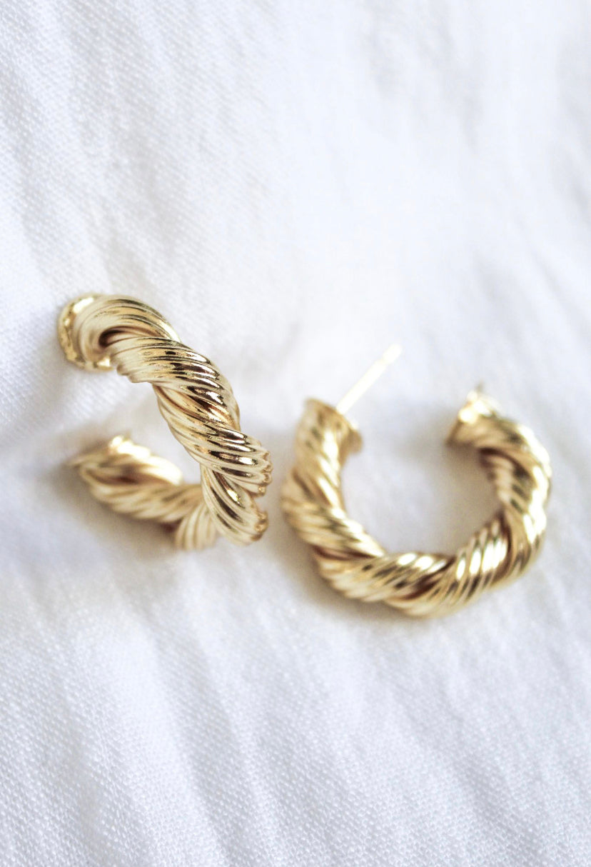 The Kinsey Designs Twisted Micayla Hoop earrings rest elegantly on a white fabric background, highlighting their timeless twisted rope style.