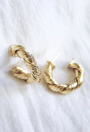 The Kinsey Designs Twisted Micayla Hoop earrings rest elegantly on a white fabric background, highlighting their timeless twisted rope style.