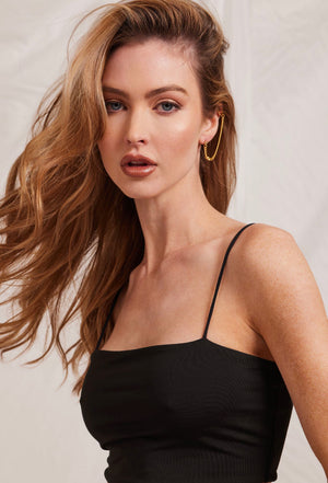 Woman with long wavy hair wears a black spaghetti strap top and Kinsey Designs' Knox Double Earrings, looking at the camera against a light background.