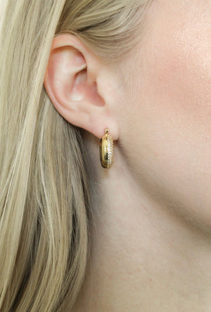 Close-up of a woman's ear wearing the Kinsey Designs Archives Mikki Pave Hoop, a gold plated earring with small crystals, visible in blonde hair; measures 0.75" wide.