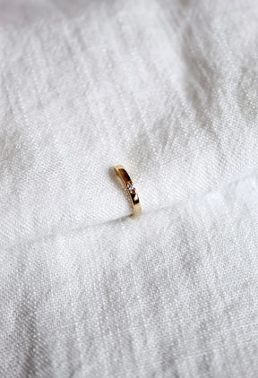 The Leni Ear Cuff by Kinsey Designs Archives, gold plated with a small cubic zirconia, rests on textured white fabric, adding understated elegance to your jewelry collection.