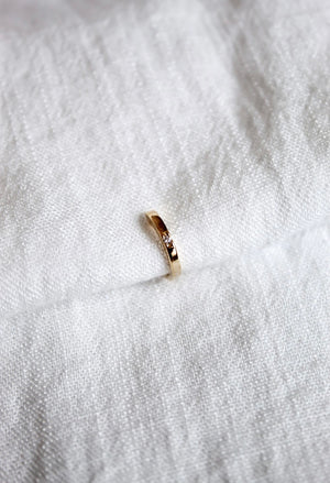 The Leni Ear Cuff by Kinsey Designs Archives, gold plated with a small cubic zirconia, rests on textured white fabric, adding understated elegance to your jewelry collection.