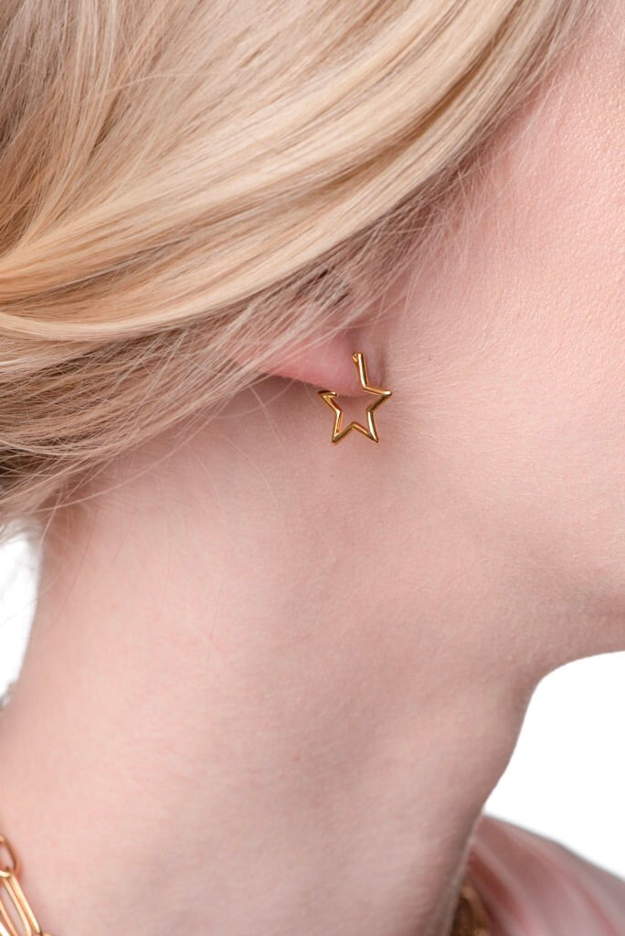 Close-up of a woman's ear with blonde hair swept back, wearing the Kinsey Designs Archives Starline earring—a 0.5” wide, gold-plated, star-shaped accessory.