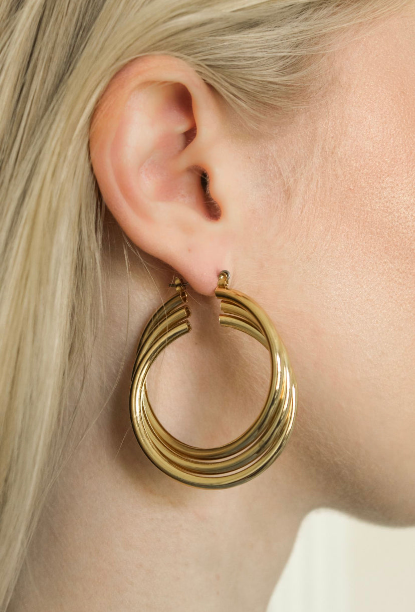 Close-up of a woman with light blonde hair wearing the Lexie Triple Hoop by Kinsey Designs Archives—a large, layered gold-plated earring measuring 2.25" long and 1.75" wide.