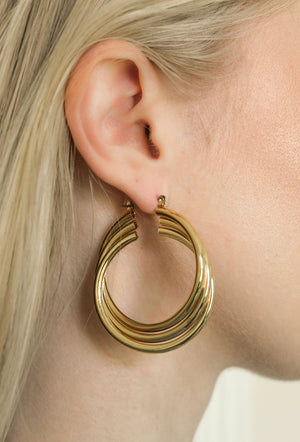 Close-up of a woman with light blonde hair wearing the Lexie Triple Hoop by Kinsey Designs Archives—a large, layered gold-plated earring measuring 2.25" long and 1.75" wide.