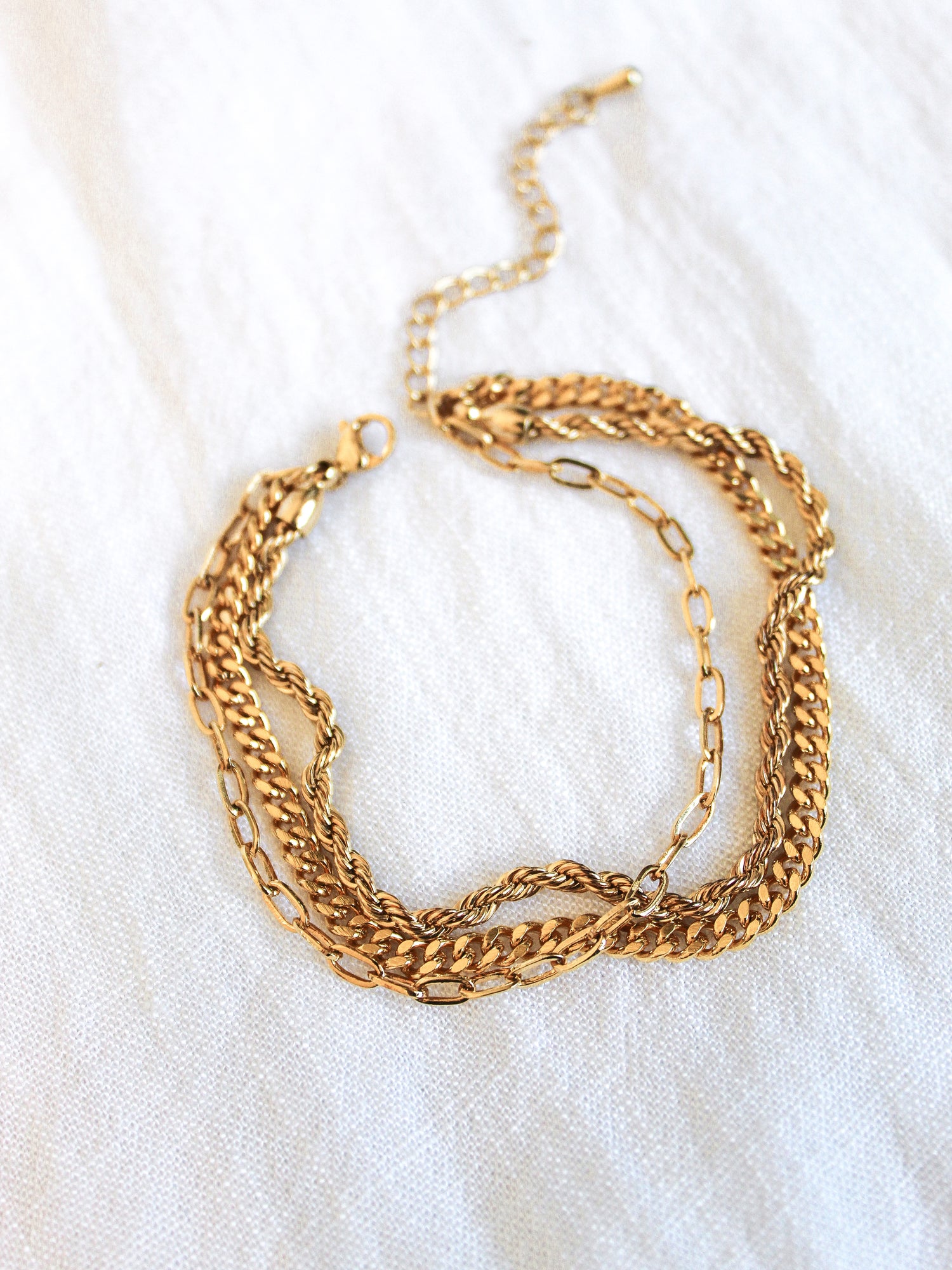 The Emmy Bracelet by Kinsey Designs Archives features gold-plated mixed link styles and a chain extender, displayed on a white fabric background.
