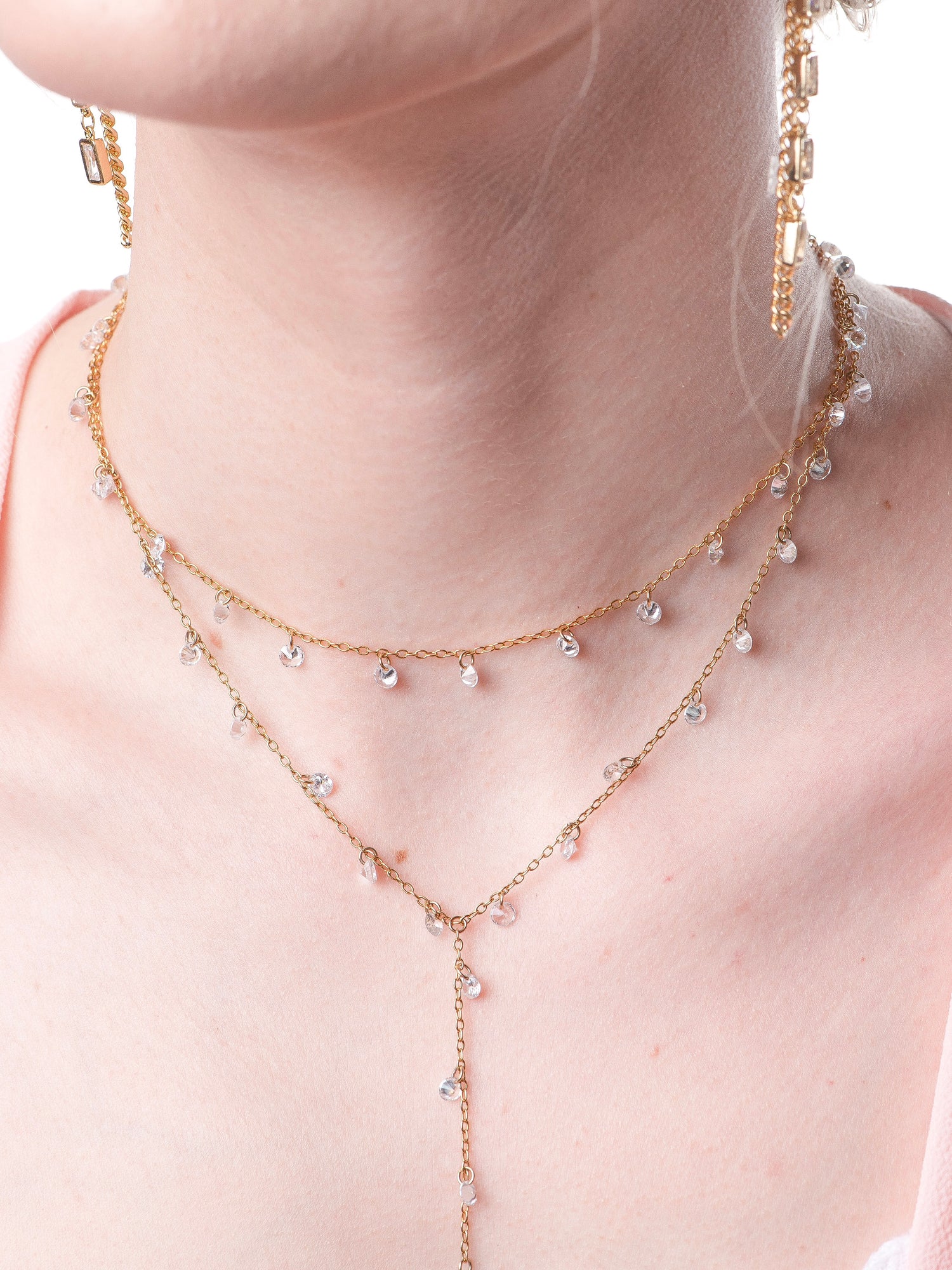 The Clare Lariat by Kinsey Designs Archives is an 18k gold plated necklace with small clear CZ charms and an adjustable extender, shown on a fair-skinned model.