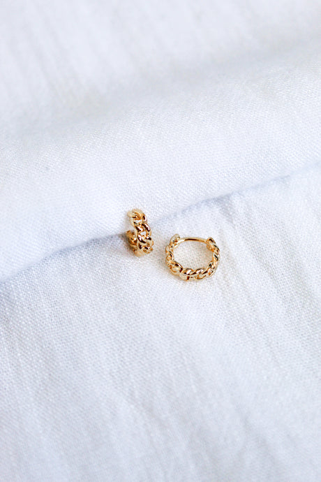 The Ivy Huggie by Kinsey Designs Archives features two small 16k gold plated brass hoops with a braided design, shown on a white fabric background.