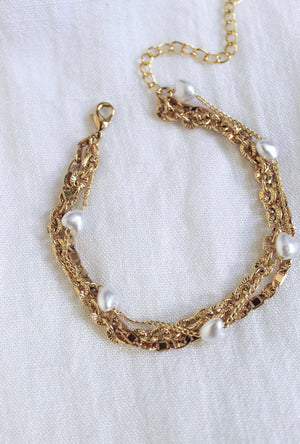 The Beyah Layer Bracelet by Kinsey Designs Archives features a gold plated brass chain with white pearls, elegantly displayed on a white fabric background.
