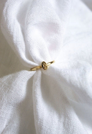 The Kinsey Initial Ring by Kinsey Designs features an engraved letter "K" and rests on soft, white textured fabric—a perfect piece of personalized jewelry.