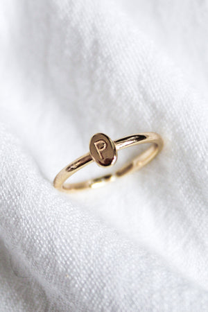 The Kinsey Designs Collection Kinsey Initial Ring with a small oval face engraved with the letter "P" is displayed on white fabric.