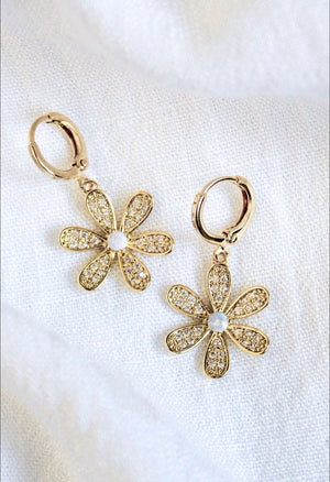 The Sandi Huggie by Kinsey Designs Archives features 16k gold plating, flower shapes with crystal petals and pearl centers, displayed on a white fabric background.