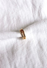 The Blurred Lines Ear Cuff by Kinsey Designs Archives, a small gold-plated double-band ear cuff, .75” wide, is displayed resting on white textured fabric.