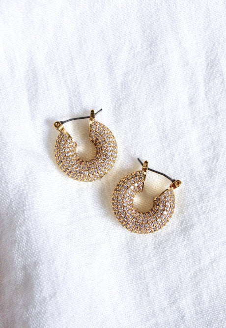 The Mikki Pave Hoop by Kinsey Designs Archives features gold plating and sparkling stones, measuring .75" wide, showcased on a white textured fabric background.