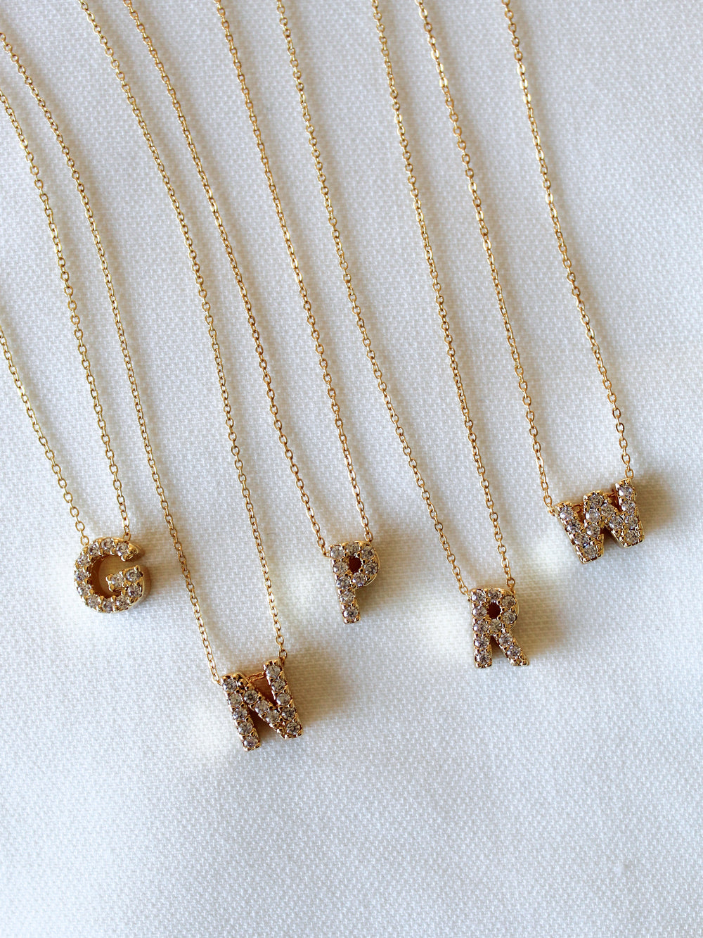 The Kinsey Designs Collection LUX Slide Initial Necklace with a gold letter C pendant is displayed on a white textured background.