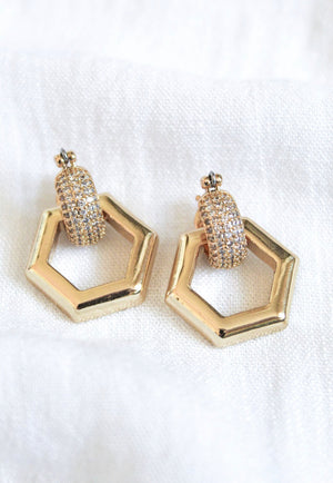 The Stevie 2-Way Hoop by Kinsey Designs Archives features gold-plated huggie earrings with removable hexagon charms and textured, cubic zirconia-studded hoops, shown on a white fabric background.