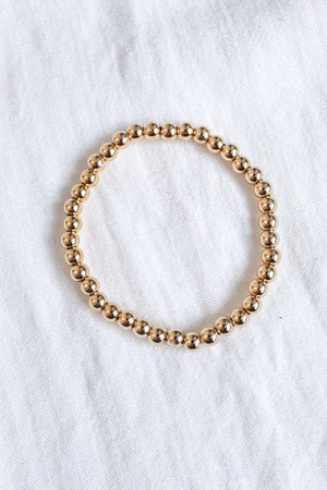The Liam Stacking Bracelet by Kinsey Designs, shown in a circle on white fabric, features an adjustable stretch design and is available in multiple sizes.