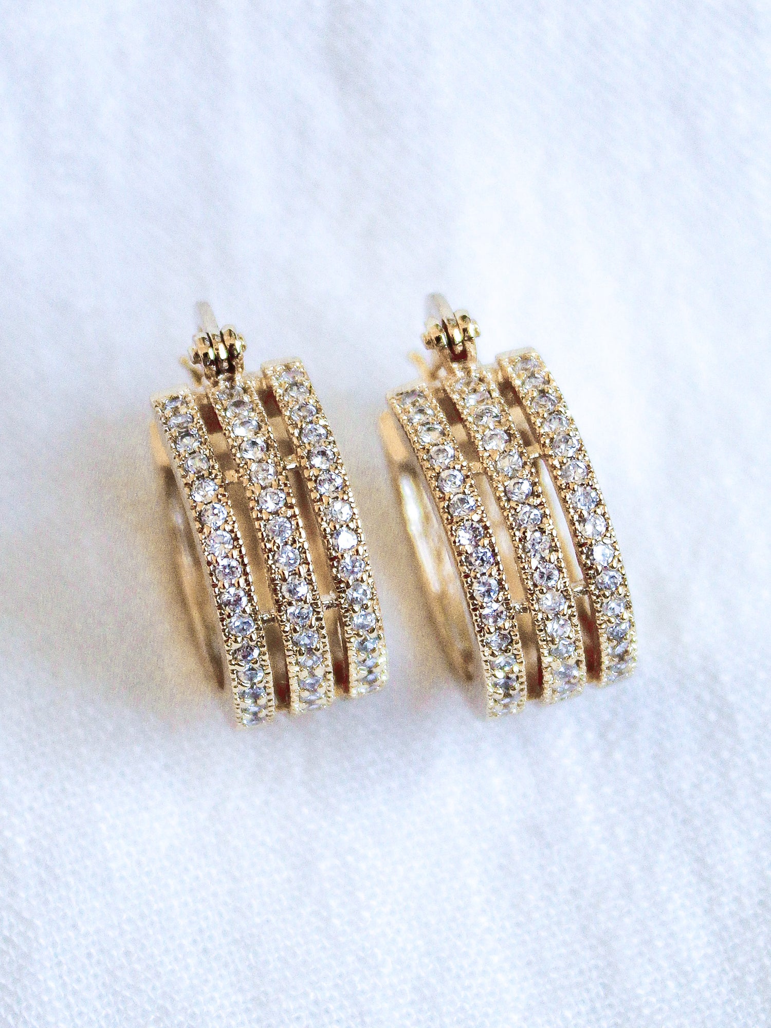 The Julia Triple Hoop by Kinsey Designs Archives features 1" gold filled hoops with three rows of sparkling cubic zirconia, shown on a white fabric background.