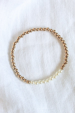 The Kinsey Designs Liam Stacking Bracelet features gold filled and white pearls on a white fabric background, with an adjustable stretch for a comfortable fit. Available in multiple sizes.