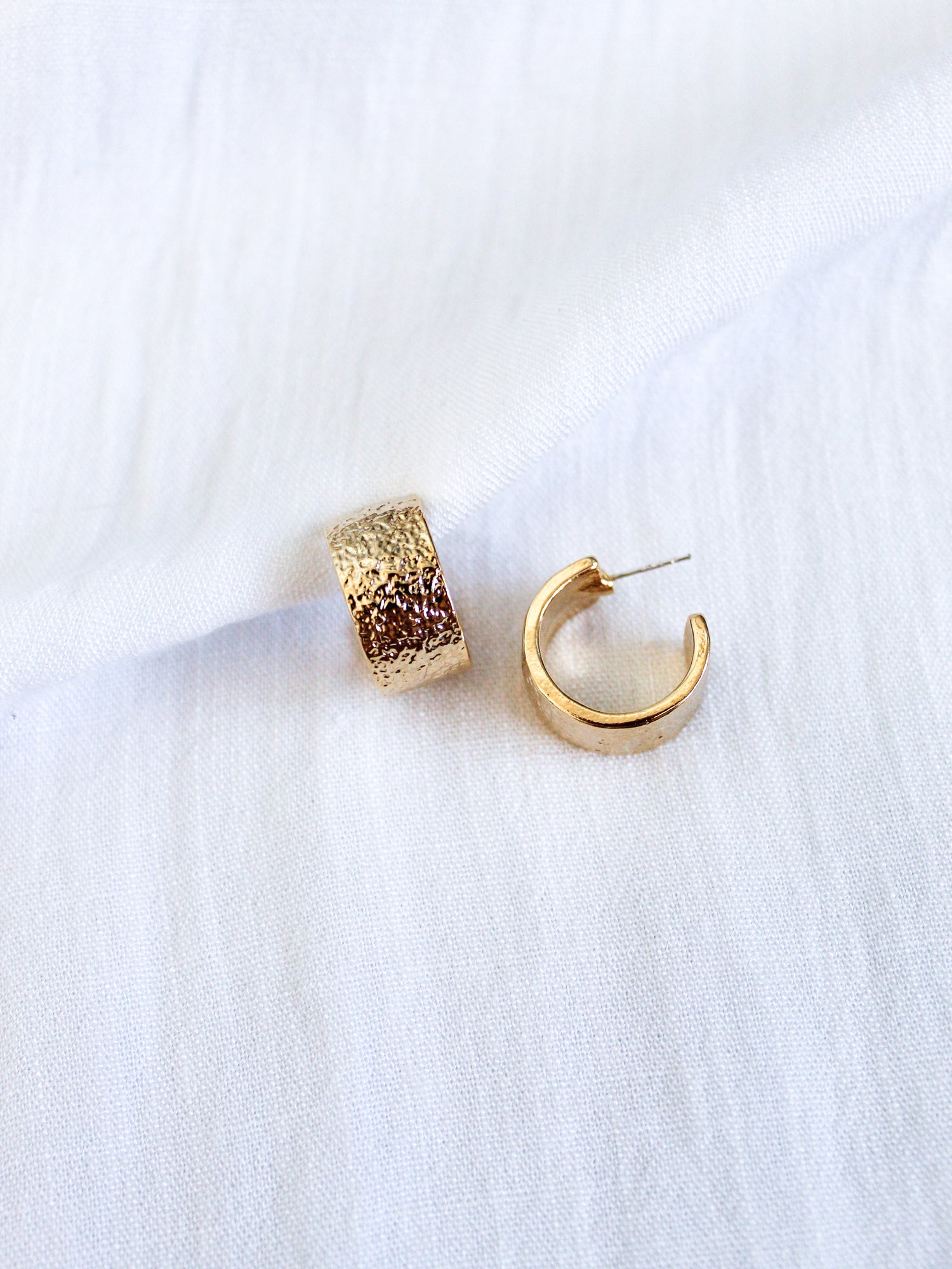 The Fawn Hoop by Kinsey Designs Archives features gold-plated brass with a textured finish, styled on white fabric. A Kinsey favorite for effortless elegance.