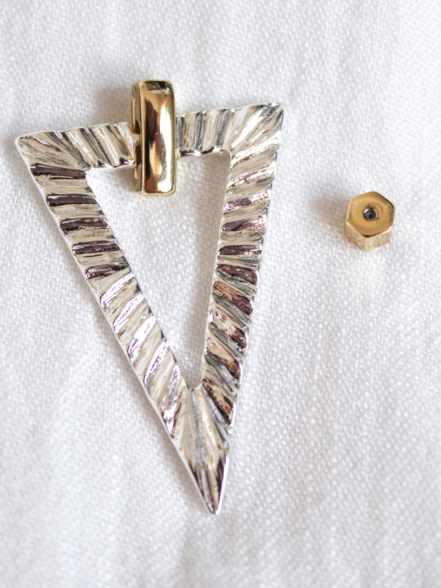 The Colin Earring by Kinsey Designs features a textured silver triangle pendant with a gold bail and a small gold hexagonal bead—ideal for pairing with your favorite gold filled earrings.