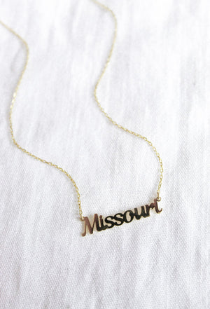 The Kinsey Designs Archives State of Mind Necklace features a gold filled "Missouri" pendant, elegantly displayed on white fabric.