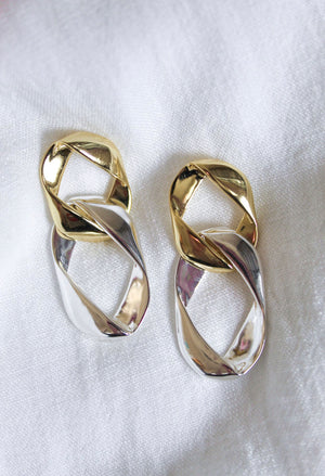 The Porter Earring by Kinsey Designs Archives features 2-inch gold and silver twisted links, 14k gold plated, shown on a white fabric background.
