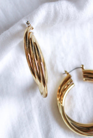 Close-up of Kinsey Designs Archives' Lexie Triple Hoop gold plated earrings, measuring 2.25" long by 1.75" wide, displayed on a white fabric background.