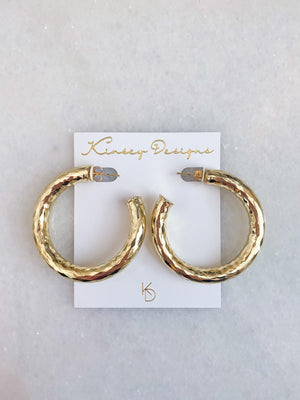 The Jasmine Hoops by Kinsey Designs are gold filled hammered hoop earrings, shown on a white Kinsey Designs card against a marble background—perfect for statement jewelry lovers.