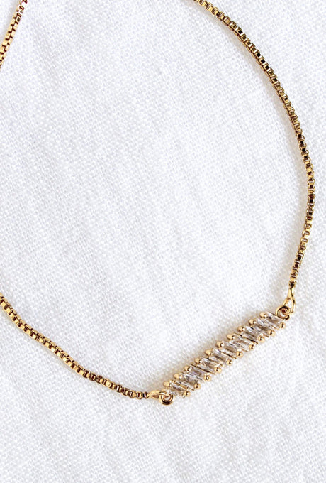 The Dupre Adjustable Bracelet by Kinsey Designs Archives features a 14k gold filled chain with sparkling cubic zirconia gemstones, showcased on a white textured fabric background.